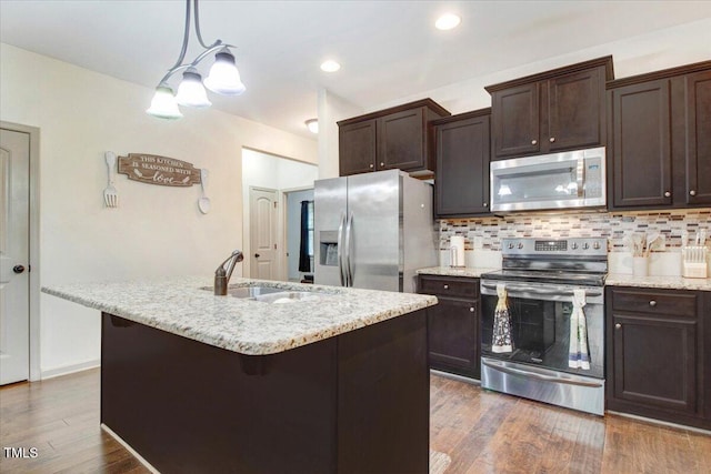 51 Balboa Pkwy, Clayton, NC 27520 - kitchen featuring appliances with stainless steel finishes, dark brown cabinets, a chandelier, decorative backsplash, and a center island with sink