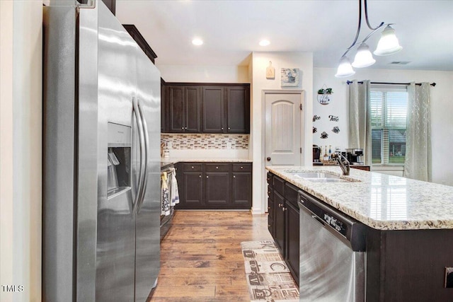 51 Balboa Pkwy, Clayton, NC 27520 - kitchen featuring stainless steel appliances, dark brown cabinets, light wood-type flooring, decorative backsplash, and pendant lighting