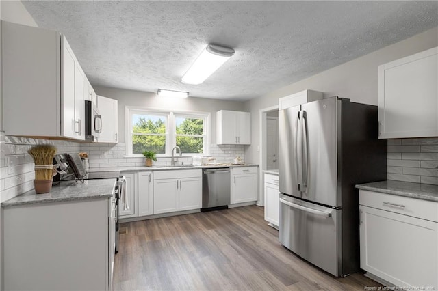 329 W Railroad St, Parkton, NC 28371 - kitchen with stainless steel appliances, backsplash, a textured ceiling, white cabinetry, and light wood-style floors