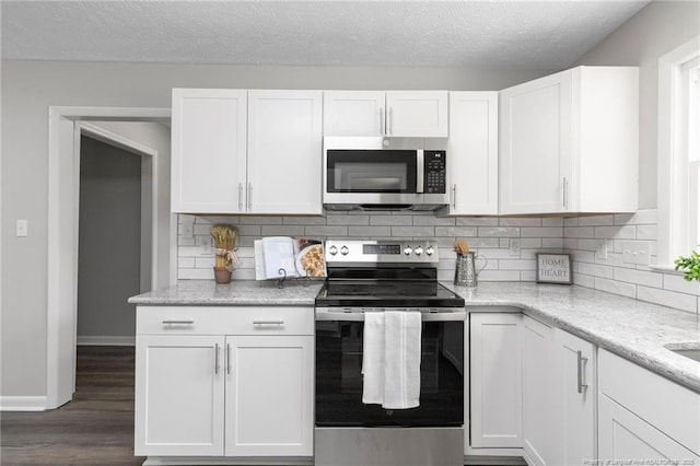 329 W Railroad St, Parkton, NC 28371 - kitchen with stainless steel appliances, white cabinets, backsplash, dark wood-style flooring, and light stone countertops