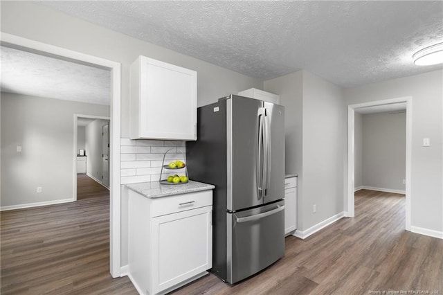 329 W Railroad St, Parkton, NC 28371 - kitchen with freestanding refrigerator, a textured ceiling, dark wood finished floors, white cabinetry, and tasteful backsplash