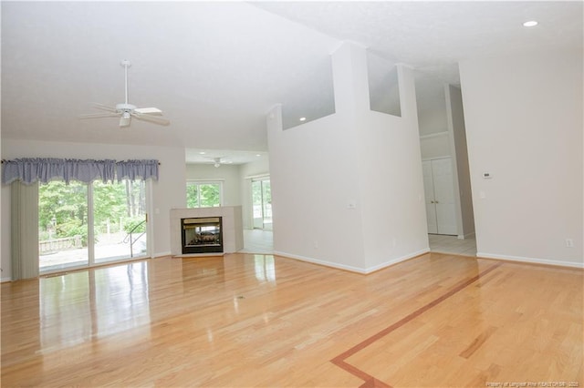 38 Windsong Pl, Whispering Pines, NC 28327 - unfurnished living room with ceiling fan, wood finished floors, high vaulted ceiling, a tiled fireplace, and recessed lighting