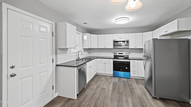 427 Elm Ct, Burlington, NC 27217 - kitchen featuring appliances with stainless steel finishes, dark countertops, dark wood-style flooring, white cabinetry, and a textured ceiling