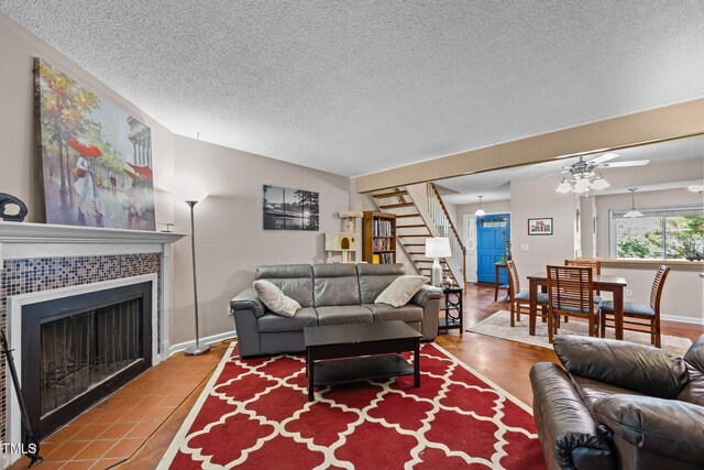 6021 Dixon Dr, Raleigh, NC 27609 - living room featuring stairs, a textured ceiling, a fireplace, and a ceiling fan