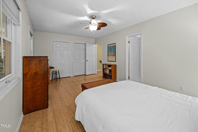 6021 Dixon Dr, Raleigh, NC 27609 - bedroom with two closets, light wood-type flooring, a textured ceiling, and a ceiling fan