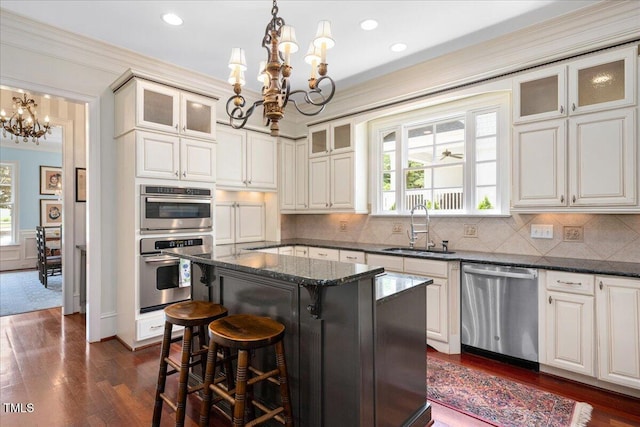 1313 Duplin Rd, Raleigh, NC 27607 - kitchen featuring appliances with stainless steel finishes, a chandelier, a breakfast bar, dark wood-type flooring, and ornamental molding