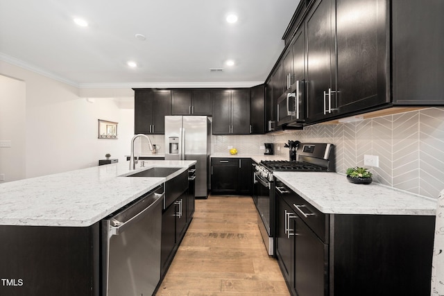 1247 White Flint Cir, Durham, NC 27703 - kitchen with stainless steel appliances, crown molding, an island with sink, tasteful backsplash, and light wood-type flooring