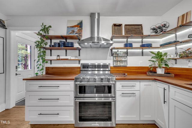 7917 Featherstone Dr, Raleigh, NC 27615 - kitchen with wall chimney exhaust hood, range with two ovens, open shelves, butcher block countertops, and white cabinetry
