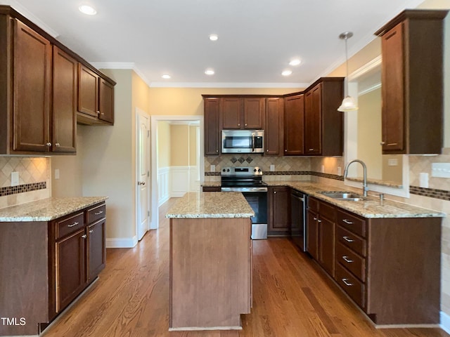 1201 Dagmar Ln, Wake Forest, NC 27587 - kitchen featuring appliances with stainless steel finishes, a center island, decorative backsplash, light stone countertops, and ornamental molding