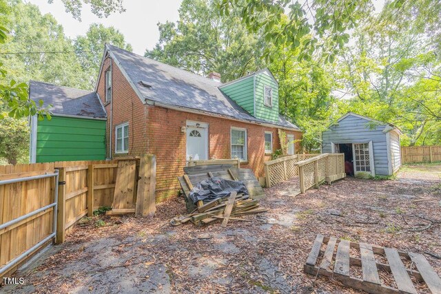 301 N King Charles Rd, Raleigh, NC 27610 - back of property featuring brick siding, a shingled roof, a chimney, and a storage shed