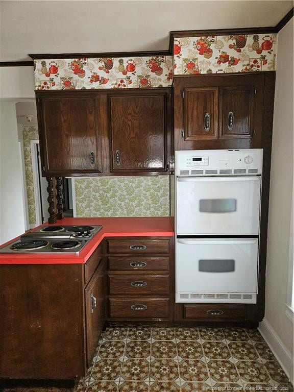 2943 Ole Bluff Mill Rd, Fayetteville, NC 28306 - kitchen with electric stovetop, double oven, dark brown cabinets, crown molding, and wallpapered walls