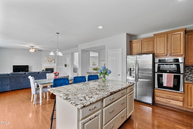 200 Woodvale Way, Fuquay Varina, NC 27526 - kitchen featuring stainless steel appliances, a kitchen breakfast bar, wood finished floors, light stone countertops, and recessed lighting