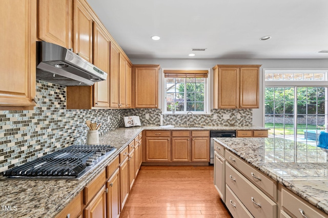 200 Woodvale Way, Fuquay Varina, NC 27526 - kitchen featuring under cabinet range hood, appliances with stainless steel finishes, light stone countertops, light wood-type flooring, and backsplash