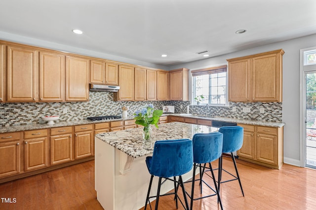 200 Woodvale Way, Fuquay Varina, NC 27526 - kitchen with under cabinet range hood, a kitchen breakfast bar, stainless steel gas stovetop, light wood-style flooring, and recessed lighting