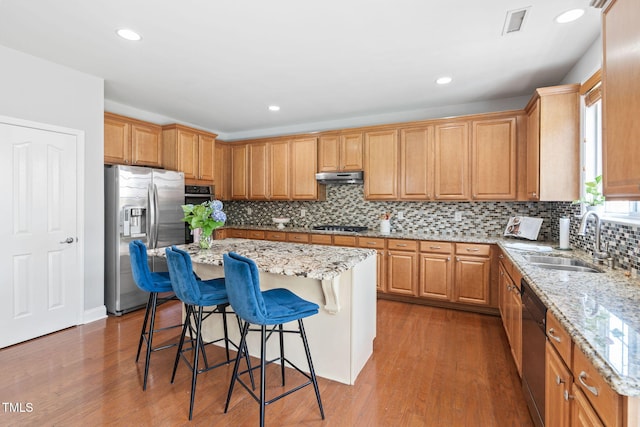 200 Woodvale Way, Fuquay Varina, NC 27526 - kitchen with appliances with stainless steel finishes, a breakfast bar, under cabinet range hood, light stone counters, and decorative backsplash