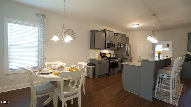 966 Airedale Trl, Garner, NC 27529 - kitchen featuring appliances with stainless steel finishes, a chandelier, gray cabinetry, dark wood-style flooring, and a kitchen bar