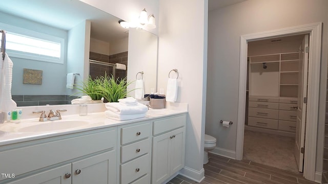 966 Airedale Trl, Garner, NC 27529 - bathroom with vanity, wood finish floors, a spacious closet, and a tile shower