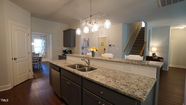 966 Airedale Trl, Garner, NC 27529 - kitchen with dark wood-style flooring, dishwasher, a center island with sink, and light stone counters