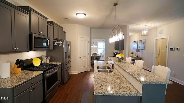 966 Airedale Trl, Garner, NC 27529 - kitchen with stainless steel appliances, a kitchen island with sink, dark wood-style flooring, decorative backsplash, and light stone counters
