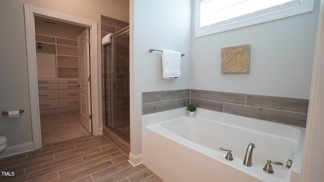 966 Airedale Trl, Garner, NC 27529 - bathroom featuring a garden tub, a spacious closet, a shower stall, and wood finished floors