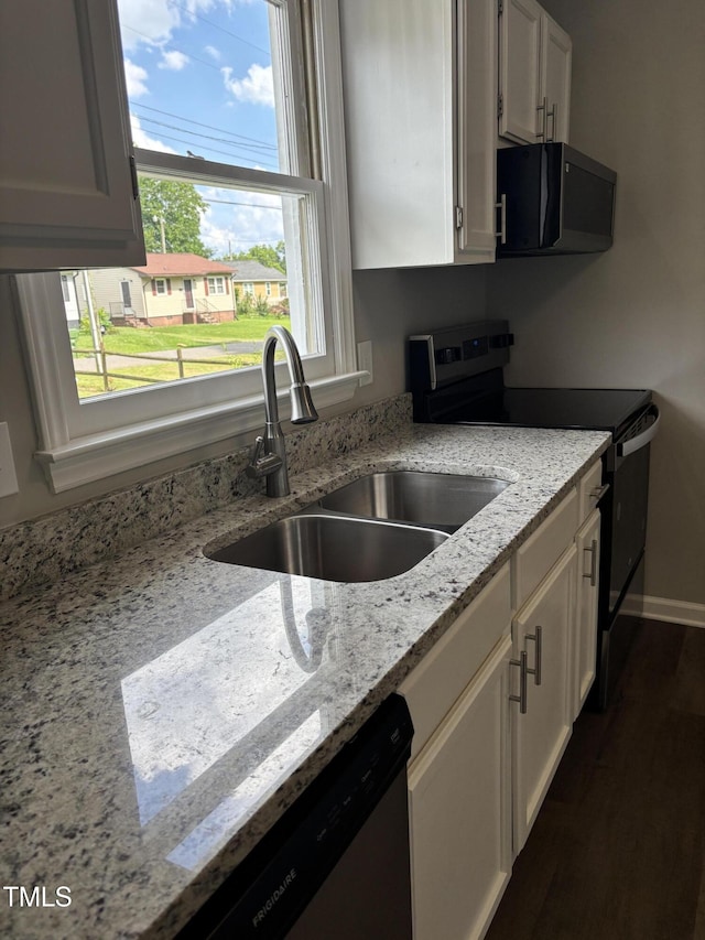 510 N St, Graham, NC 27253 - kitchen with electric range, black microwave, stainless steel dishwasher, white cabinetry, and light stone counters