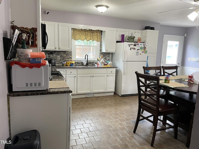 3129 Skycrest Dr, Raleigh, NC 27604 - kitchen with freestanding refrigerator, black microwave, dark countertops, tasteful backsplash, and white cabinets