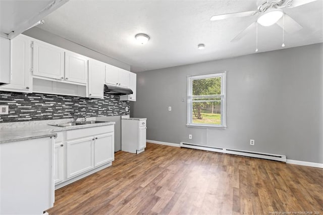 6547 Amanda Cir, Fayetteville, NC 28304 - kitchen with baseboard heating, tasteful backsplash, white cabinetry, wood finished floors, and under cabinet range hood