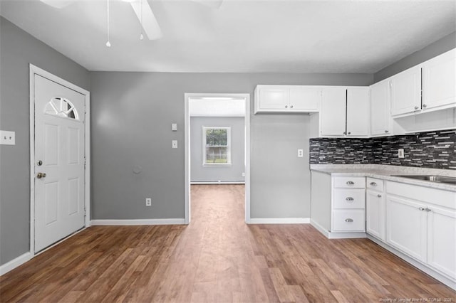 6547 Amanda Cir, Fayetteville, NC 28304 - kitchen featuring light wood-style flooring, light countertops, a ceiling fan, white cabinets, and backsplash