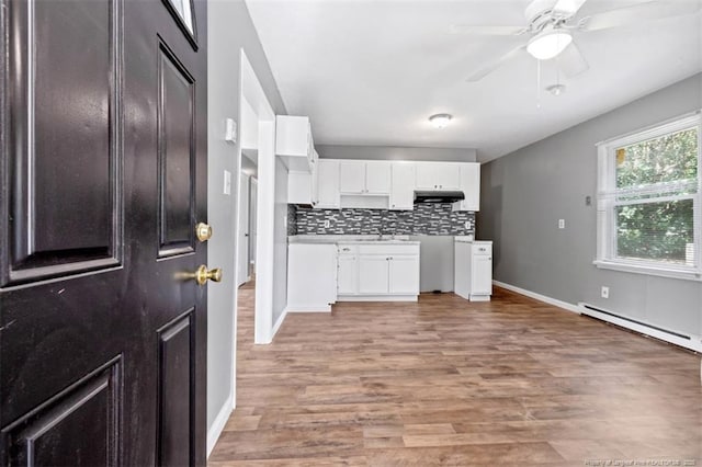 6547 Amanda Cir, Fayetteville, NC 28304 - kitchen featuring a baseboard radiator, white cabinets, backsplash, light wood-type flooring, and under cabinet range hood