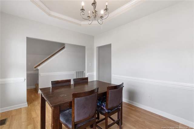 229 Red Oak Ct, Raeford, NC 28376 - dining space featuring a chandelier, light wood-style floors, a tray ceiling, ornamental molding, and stairs