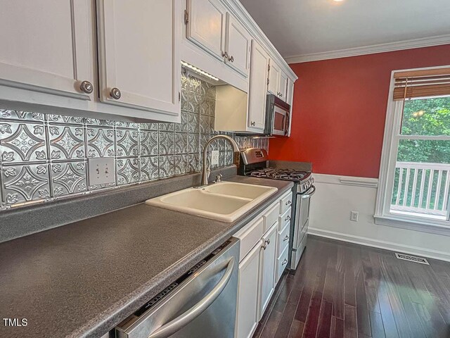 5500 Fortunes Ridge Dr Unit 94C, Durham, NC 27713 - kitchen featuring appliances with stainless steel finishes, white cabinetry, dark countertops, ornamental molding, and dark wood-style flooring