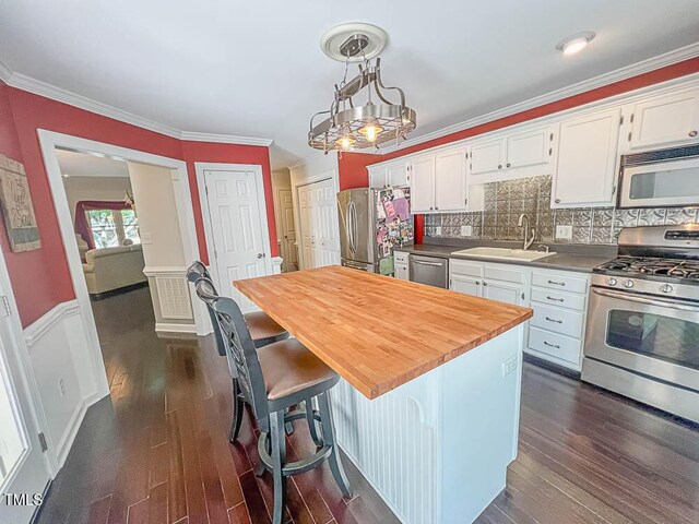 5500 Fortunes Ridge Dr Unit 94C, Durham, NC 27713 - kitchen featuring appliances with stainless steel finishes, white cabinets, dark wood finished floors, decorative backsplash, and ornamental molding