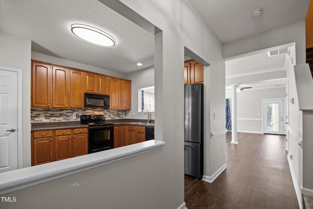 3408 Sosa Rd, Raleigh, NC 27610 - kitchen featuring black appliances, brown cabinets, a textured ceiling, dark wood-style floors, and decorative backsplash