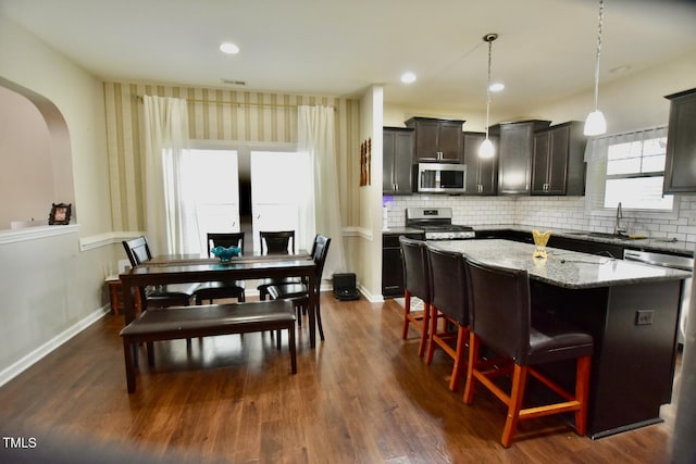 83 Mariners Point Way, Garner, NC 27529 - kitchen featuring stainless steel appliances, a kitchen island, light stone counters, dark wood-type flooring, and a kitchen breakfast bar