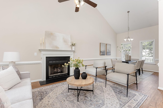 202 Chapel Valley Ln, Apex, NC 27502 - living room featuring high vaulted ceiling, wood finished floors, ceiling fan, a fireplace with raised hearth, and a chandelier