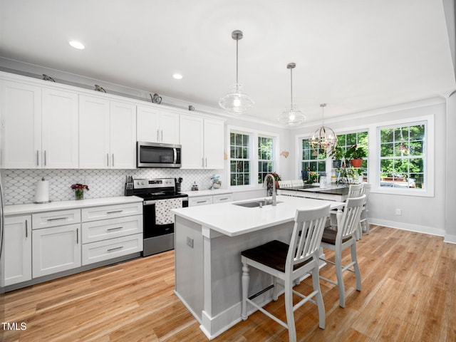 1176 Sagamore Dr, Louisburg, NC 27549 - kitchen with stainless steel appliances, decorative backsplash, white cabinetry, a breakfast bar area, and light wood-type flooring
