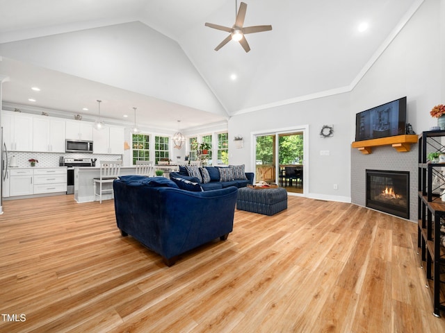 1176 Sagamore Dr, Louisburg, NC 27549 - living area featuring a ceiling fan, healthy amount of natural light, a glass covered fireplace, high vaulted ceiling, and light wood-style floors