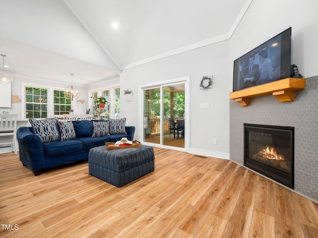 1176 Sagamore Dr, Louisburg, NC 27549 - living room featuring wood finished floors, a glass covered fireplace, plenty of natural light, high vaulted ceiling, and ornamental molding