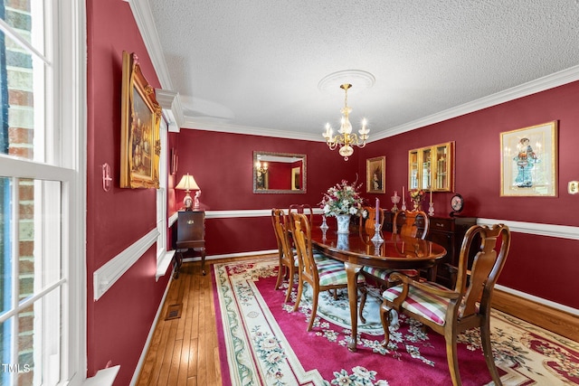 116 Lost Tree Ln, Cary, NC 27513 - dining room with wood-type flooring, ornamental molding, a chandelier, and a textured ceiling