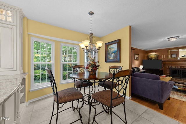 116 Lost Tree Ln, Cary, NC 27513 - dining space with a fireplace, a chandelier, light tile patterned flooring, and plenty of natural light