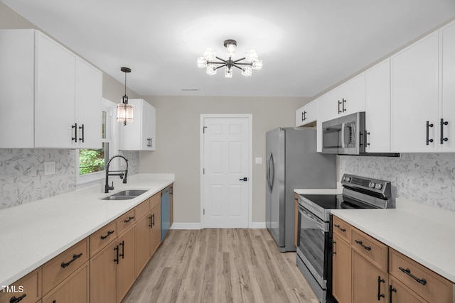 1605 Nixon St, Durham, NC 27707 - kitchen featuring appliances with stainless steel finishes, a chandelier, light wood-style floors, tasteful backsplash, and light countertops