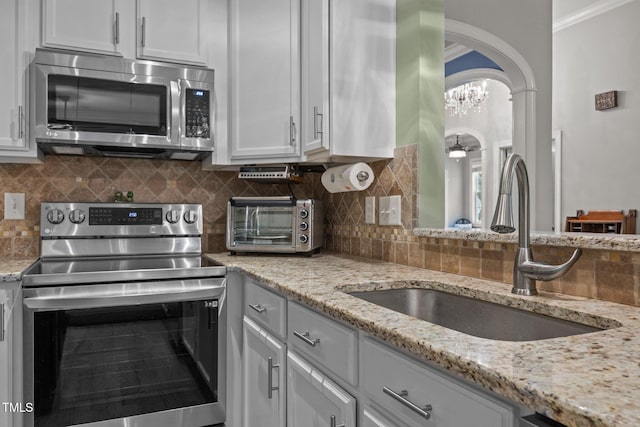 8116 Mosby Way, Willow Springs, NC 27592 - kitchen featuring appliances with stainless steel finishes, arched walkways, decorative backsplash, light stone countertops, and ornamental molding