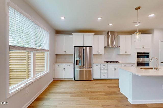2735 Hunter Woods Dr # 571, Apex, NC 27502 - kitchen featuring appliances with stainless steel finishes, wall chimney range hood, light countertops, light wood-style flooring, and white cabinetry