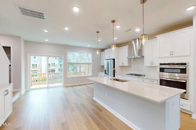 2735 Hunter Woods Dr # 571, Apex, NC 27502 - kitchen with stainless steel appliances, wall chimney exhaust hood, a kitchen island with sink, light countertops, and recessed lighting