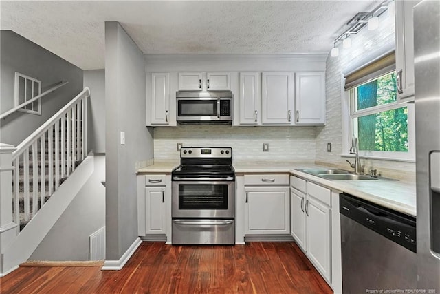 6405 Riegelwood St, Fayetteville, NC 28314 - kitchen with appliances with stainless steel finishes, dark wood-type flooring, a textured ceiling, light countertops, and decorative backsplash