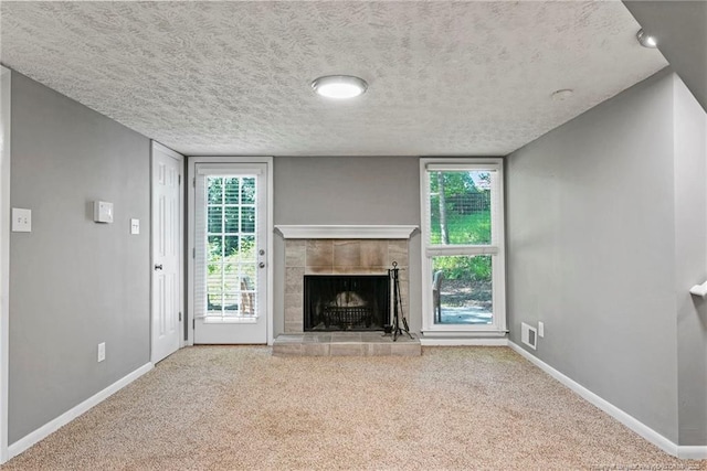6405 Riegelwood St, Fayetteville, NC 28314 - unfurnished living room featuring carpet flooring, a tile fireplace, a textured ceiling, and healthy amount of natural light