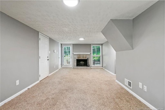 6405 Riegelwood St, Fayetteville, NC 28314 - unfurnished living room featuring a textured ceiling, a fireplace with raised hearth, and carpet flooring