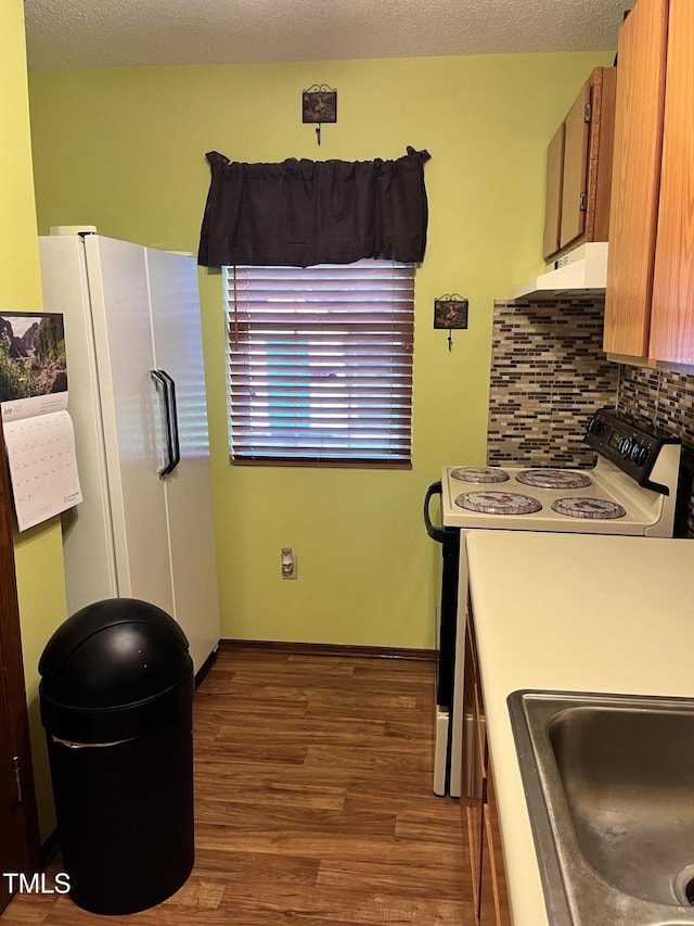 469 Whitehead Rd, Enfield, NC 27823 - kitchen featuring white appliances, dark wood-style flooring, tasteful backsplash, brown cabinetry, and under cabinet range hood