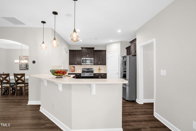 304 Garden Walk Dr, Durham, NC 27703 - kitchen featuring appliances with stainless steel finishes, a kitchen breakfast bar, dark brown cabinetry, tasteful backsplash, and dark wood-style floors