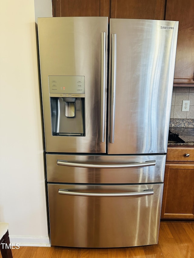 1150 Brookhill Way, Cary, NC 27519 - kitchen view of stainless steel refrigerator with ice dispenser, light wood-type flooring, decorative backsplash, brown cabinetry, and dark stone countertops
